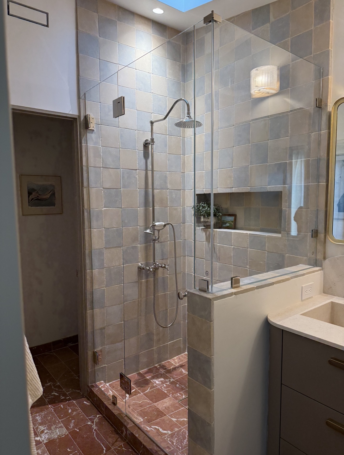 Frameless glass shower enclosure in a sunlit minimalist bathroom